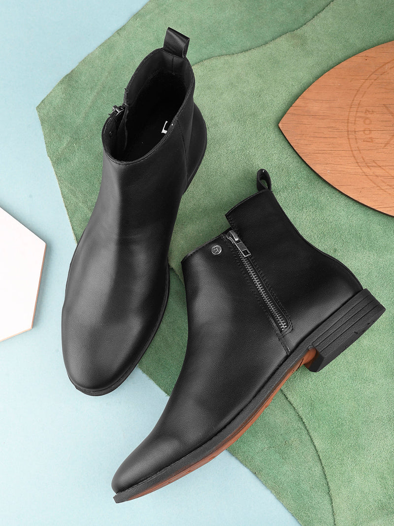 A sleek black leather Chelsea boot with a side zipper, pull-tab at the back, and a low block heel.