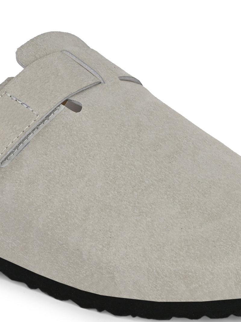 Nude suede slip-on clog with a black rubber sole and adjustable strap.
