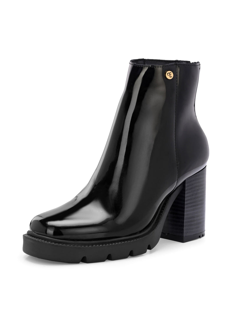 Glossy black patent leather ankle boot with a chunky block heel, lug sole, and a gold logo detail near the collar.