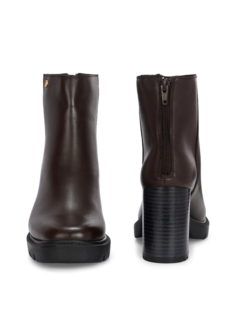 Glossy brown patent leather ankle boot with a chunky block heel, lug sole, and a gold logo detail near the collar.