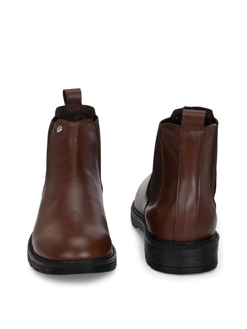 Brown Chelsea boots with elastic side panels, a pull-tab at the heel, rounded toe, and a small metallic brand logo near the ankle.