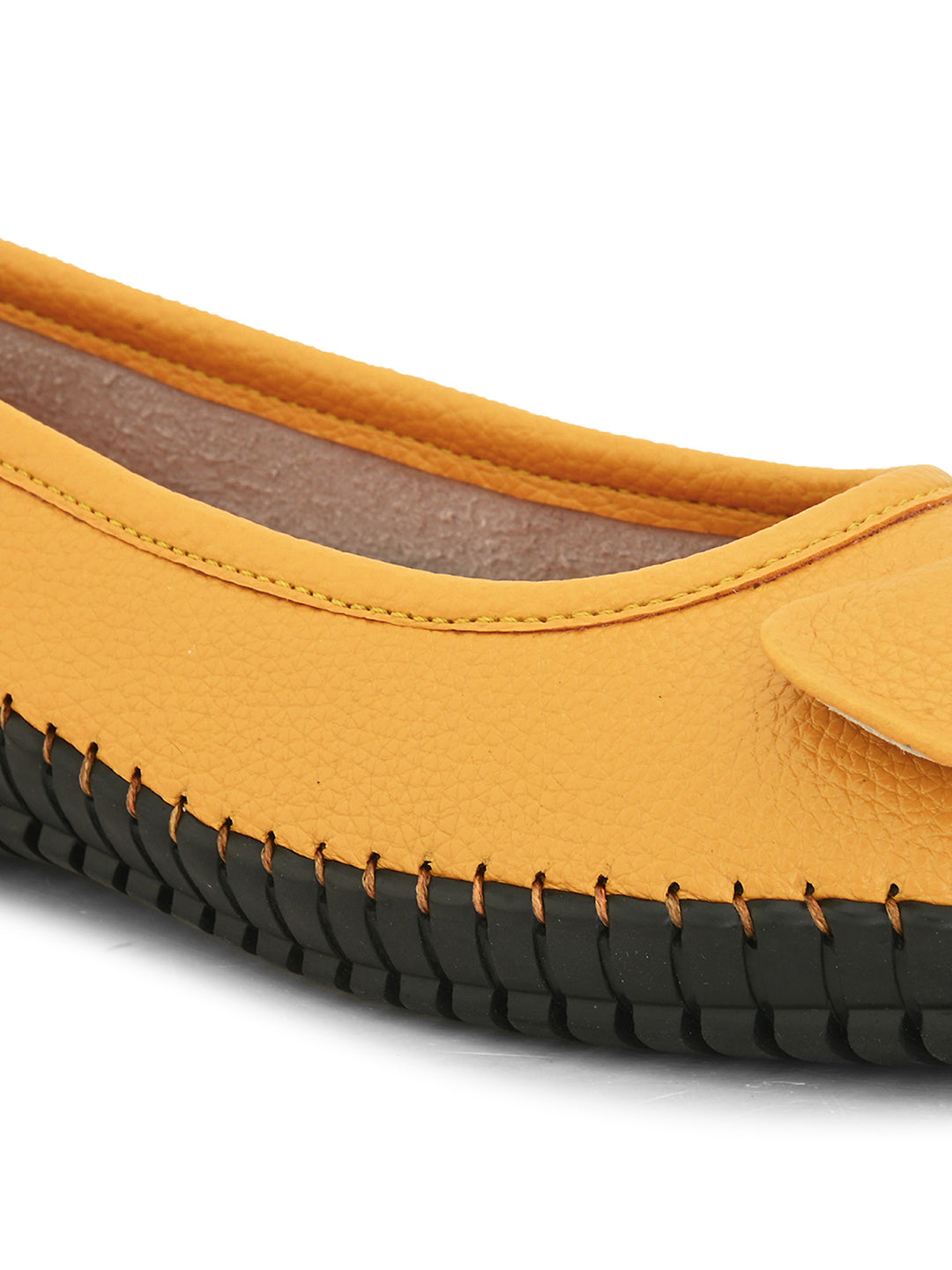Mustard yellow leather flat shoe with a decorative bow, black textured sole, and visible stitching for a casual, stylish look.