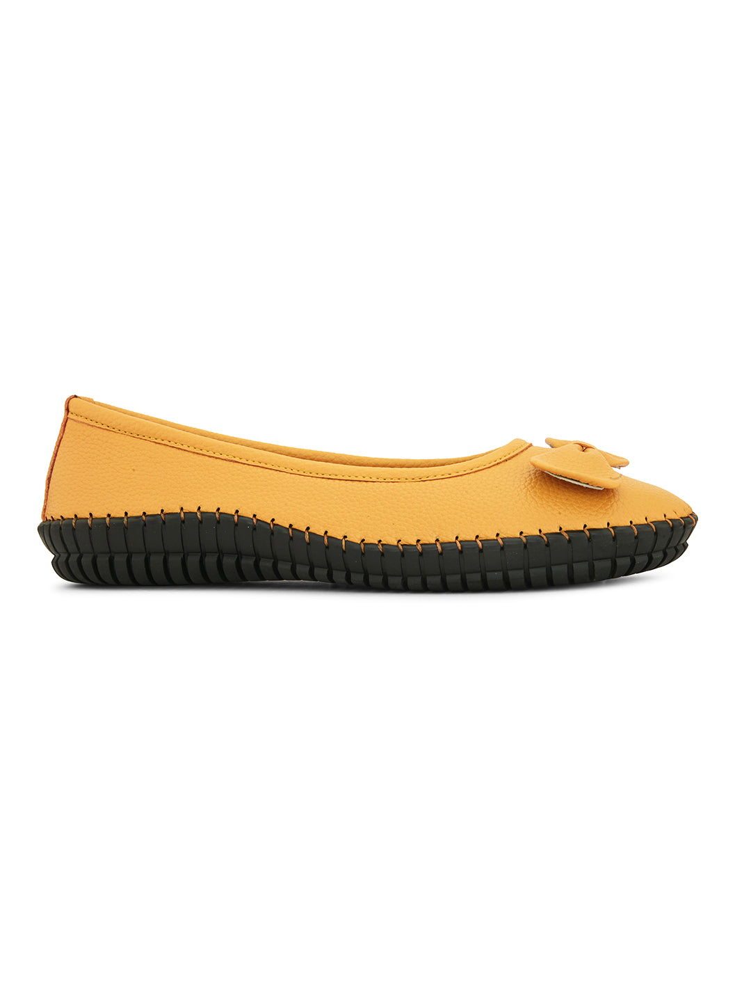 Mustard yellow leather flat shoe with a decorative bow, black textured sole, and visible stitching for a casual, stylish look.